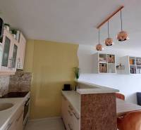 A kitchen in a 2-room apartment with hanging lights and a wooden table.