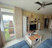 Living room in a 2-room apartment with a balcony, TV wall, and ceiling fan.