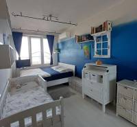 Children's room with two beds, a blue wall, and plenty of storage space.