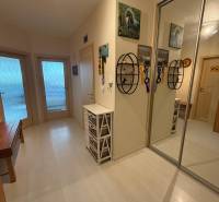 A hallway in a 2-room apartment with white furniture and a mirrored wardrobe.