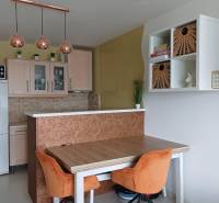 Dining area in a 2-room apartment with orange chairs and pendant lamps.