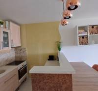 A kitchen in a 2-room apartment with soft pastel colors and pendant lights.