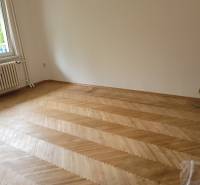 An empty room in a 3-room apartment with a parquet floor and a window.