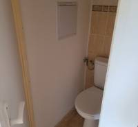 A toilet with tiles and entrance doors in a 3-room apartment.