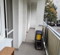 A balcony in a 3-room apartment with folding chairs and a view of the trees in the yard.