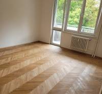 A room in a 3-room apartment with wooden flooring and balcony doors.