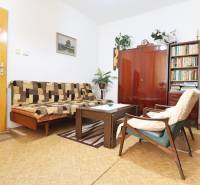 Living room in a family house with wooden furniture, carpets, and a bookshelf.