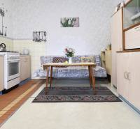A kitchen in a family house with older equipment, a gas stove, and a sofa.