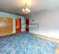 A room in a cottage with a carpeted floor, a wardrobe, a mirror, and a pendant light.