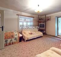 Living room in a cottage with comfortable sofas, a carpet, and a cabinet with porcelain.