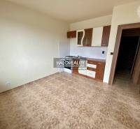 Kitchen in a studio apartment with tiled floor and cabinets.