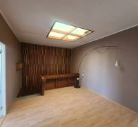 A room in a family house with wooden panels and flooring, lighting with a decorative element.
