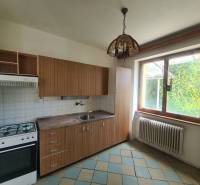 A kitchen with wooden cabinets in a family house, large window, gas stove.