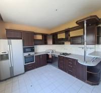 A family house kitchen with built-in appliances and a dining counter.