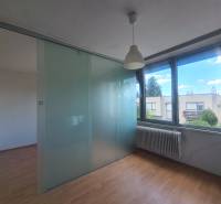 Interior of a family house with a glass partition, wooden floor, and large windows.