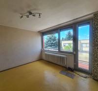 A room with a yellow floor, large windows, and a patterned wall in a family house.