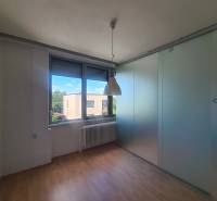 Interior of a family house with laminate flooring, a radiator, and sliding glass doors.