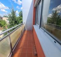 A balcony of a family house in Nové Zámky with tiles and a view of the trees.