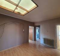 Interior of a family house with an empty room, parquet floor, and brick wall.