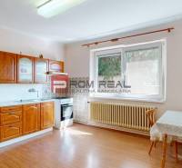 A kitchen in a family house with a wooden cabinet, table, and a large window by the radiator.