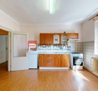 A kitchen in a family house with a wooden floor, cabinets, and a gas stove.