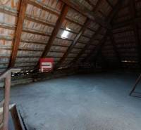 The attic of a family house with wooden beams and a concrete floor.
