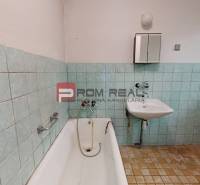 A bathroom in a family house with a bathtub, a sink, and older tiles.