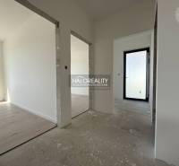The interior of a family house with a concrete floor and white walls, through open doors.