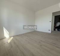 A room with a wooden floor in a family house, white walls, and open doors.