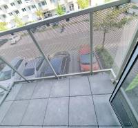 A balcony with a view of the parking lot and trees from a 3-room apartment.