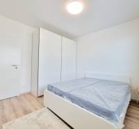 A bedroom in a 3-room apartment with a bed, a white wardrobe, and wooden flooring.