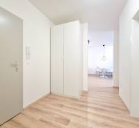 A bright hallway with wooden flooring and white furniture in a 3-room apartment.