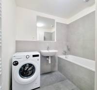 Bathroom in a 3-room apartment with a bathtub, washing machine, and sink.