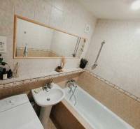 Bathroom with a bathtub and a washing machine in a 3-room apartment, subtle decorations and a mirror.