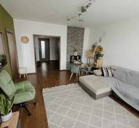 Living room with a brown floor and a gray sofa in a three-room apartment.