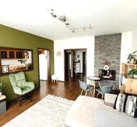 Living room with wooden flooring and a green wall in a three-room apartment.