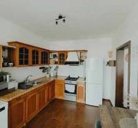 A kitchen in a 3-room apartment with wooden cabinets, a white refrigerator, and a stove.