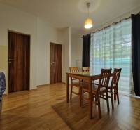 Dining room in a one-room apartment with wooden furniture and glass doors.
