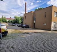 Parking lot on Tehelná Street in Pezinok with cars and a building, place for a 1-room apartment.