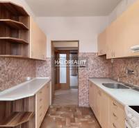 A kitchen in a 3-room apartment with wooden cabinets and tiled backsplash.