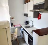 A kitchen in a 2-room apartment with a refrigerator, dishwasher, cabinets, and appliances.