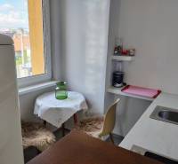 A kitchen in a 2-room apartment with a window, a bar counter, and a dining area.