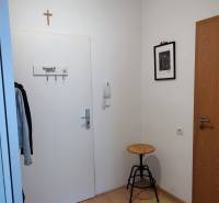 Hallway of a 2-room apartment with a coat rack, chair, and carpet.