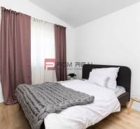 Bedroom in a 3-room apartment with a bed, gray blanket, and nightstand.
