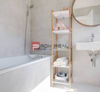 A bathroom in a 3-room apartment with a bathtub, open shelf, and mirror on the wall.