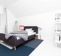 A bedroom in a 3-room apartment with a modern bed, a shelf, and white walls.
