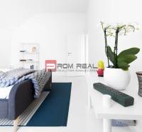 A bedroom with a bed, white furniture, and decorations in a three-room apartment.