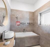 A bathroom with a bathtub and a sink in a 3-room apartment, simplicity and light tones.
