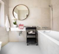 A bathroom in a 3-room apartment with a bathtub, a mirror, and a window, decorated with a flower.