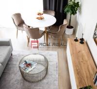 Dining area in a 3-room apartment with a round table, sofa, and carpet.